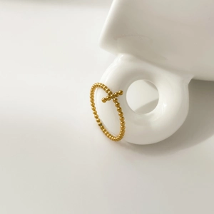 Macro shot of gold beaded cross ring hanging on white ceramic, showing refined craftsmanship