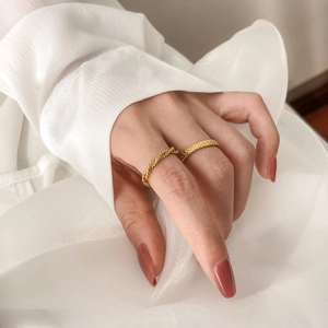 Close-up of golden minimalist twisted rope and woven texture rings on model hand