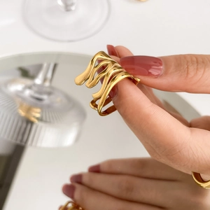Gros plan sur la bague cœur évidée dorée au design minimaliste et vagues abstraites