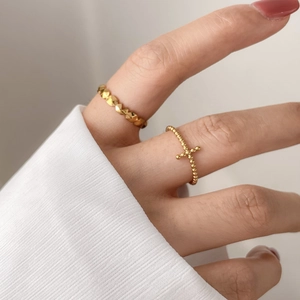 Minimalist gold ring set with geometric facets and cross bead design on a hand