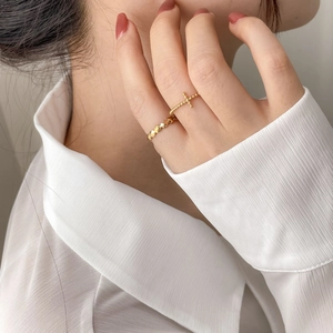 Detail of stacked gold rings featuring cross charm and geometric faceted metal band