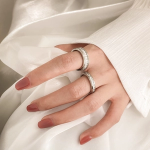 Macro detail of sparkling stacked rhinestone rings on finger with elegant silk background