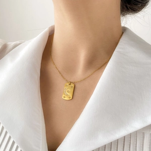 Minimalist gold titanium steel necklace with celestial sun and moon pendant on a model