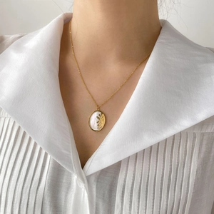 Detail of gold sun face and mother of pearl inlay pendant on a minimalist necklace