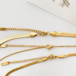 Detail of gold snake chain with lobster clasp and K18 hallmark tag on white background