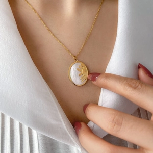 Elegant gold titanium sun pendant necklace with mother of pearl inlay on model