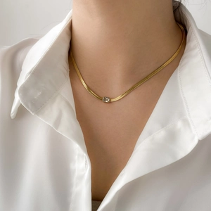 Detailed close-up of a golden flat snake chain necklace with a square zircon pendant