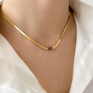 Close-up of golden flat snake chain necklace with a rectangular purple zircon gemstone