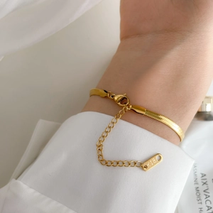 Macro detail of gold snake chain with K18 engraved tag on adjustable link closure