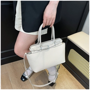 Detail van de gebroken witte tote tas van lycheeleer met zilveren gesp en handvat