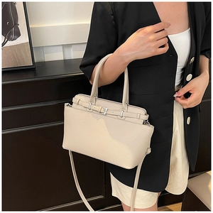 Beige tote bag met litchi-korrel en zilveren gesp gedragen door model in blazer