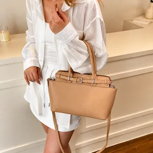 Detail van beige handtas van generfd leer met gespriem en verstelbare schouderriem