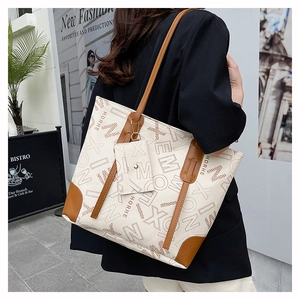 Détail d'un sac cabas beige avec bordure en cuir marron et motifs de monogrammes