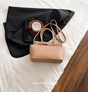 Detailopname van de abrikooskleurige tote bag met lycheestructuur en metalen gesp