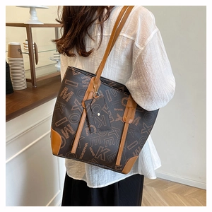 Detail of large brown monogram tote bag with matching detachable pouch in cafe setting