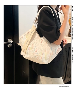 Close-up of white quilted tote bag featuring colorful embroidery and canvas shoulder strap
