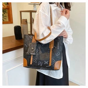 Close-up of leather handle and printed letters on large tote bag with mini card pouch