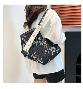 Quilted black tote bag featuring colorful wave embroidery and a wide beige shoulder strap