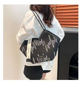 Detail of black quilted tote bag featuring colorful zigzag embroidery and wide canvas strap