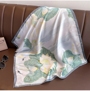 Detailed view of silk scarf with lotus and koi fish prints on a leather surface
