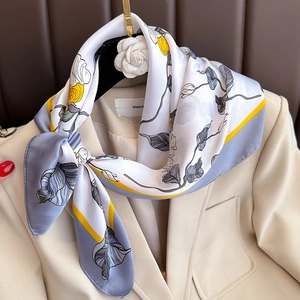 Élégant foulard en soie à imprimé floral jaune et gris porté sur un blazer de bureau