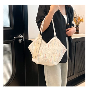 Detail of white striped canvas tote bag showing colorful embroidery and textured fabric
