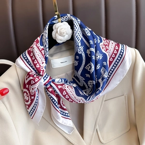 Elegant red, blue, and white floral silk scarf styled with a beige blazer and camellia