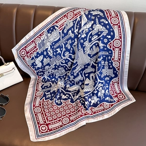 Elegant silk scarf with city illustration print on dark brown leather sofa with handbag