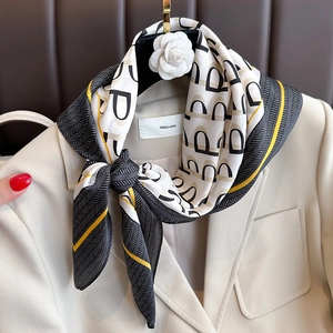Elegant silk scarf with geometric letter print styled on a beige blazer and hanger