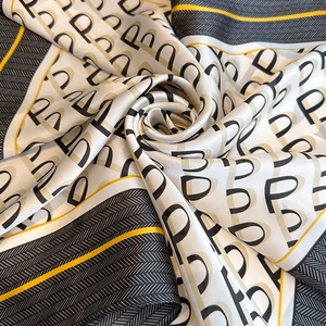 Detail of silk scarf showing letter P pattern and soft texture with contrast border