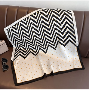 Carré de soie à pois et motifs zigzag posé sur un canapé en cuir avec accessoires