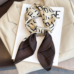 Elegant geometric letter silk scarf with brown herringbone pattern on a cream blazer