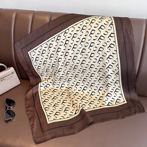 Detail of silk square scarf with P-letter pattern and herringbone border on leather background