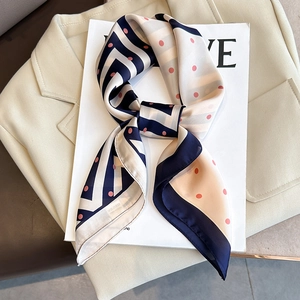 Foulard en soie style français à pois et rayures posé sur un blazer beige élégant