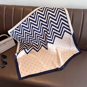Carré de soie élégant à pois bleu marine et rose, disposé sur un fond en cuir