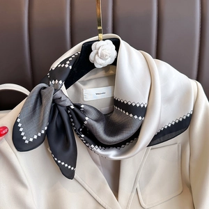 Elegante foulard in seta bianco e nero con motivi geometrici su una giacca beige da ufficio