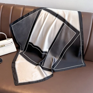 Elegante sciarpa in seta con motivi geometrici su divano in pelle con borsa bianca