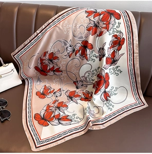 Detail eines eleganten Satin-Blumenschals mit roten Blüten auf braunem Lederhintergrund
