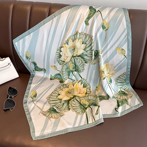 Elegant silk scarf with lotus print displayed on leather sofa with classic accessories