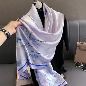 Écharpe élégante en soie violette à fleurs avec bordure bleue sur un sac à main beige