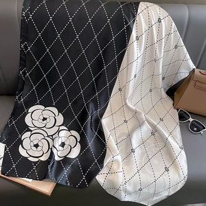 Elegant camellia silk scarf with quilted diamond pattern on luxury leather background