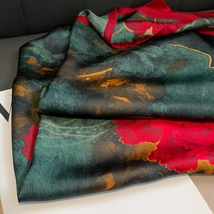 Macro view of silk-like floral scarf showing deep green fabric and peony patterns