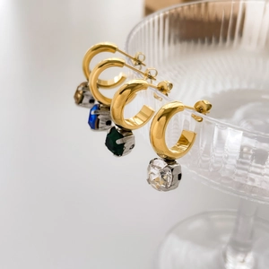 Detail of four-color C-shaped drop earrings with colorful gemstones and gold claw settings