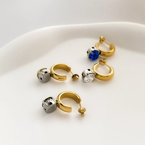 Chic asymmetric C-shaped gold earrings set with multi-colored square gemstones on white ceramic