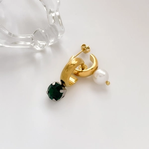 Detail view of gold hoop earrings with asymmetric green gemstone and white pearl drops