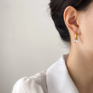 French style gold hoop earrings with asymmetric square clear gemstone on a model