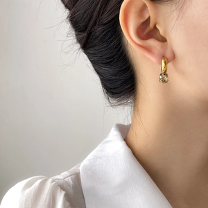 Close-up of asymmetrical golden earring with a champagne gemstone on model ear