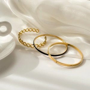 Detailed close-up of a three-piece gold-plated bracelet set with honeycomb and black enamel