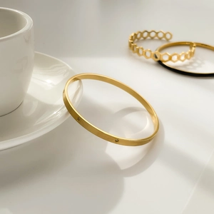 Macro view of gold minimalist honeycomb hollow bangle and hexagram star bracelet