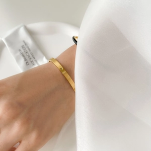 Detailed close-up of a slim gold honeycomb bracelet with star engravings on a model wrist